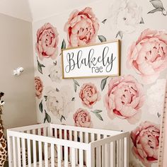 a baby's room decorated in pink and white with flowers on the wall, giraffe standing next to it