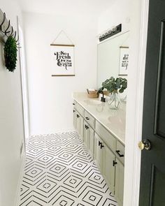 An arrangement of black and white geometric-patterned tiles stands out in this modern boho bathroom. Gray cabinets complement the black handles and coordinated faucet. Decorate the white countertop with a vase of leaves to add color to the room...   Image: randrathome