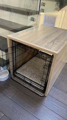 a dog crate sitting on the floor next to a stair case with its door open