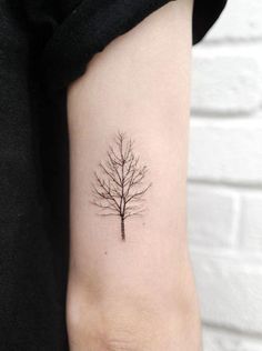 a small tree tattoo on the left inner arm, with no leaves or branches in it