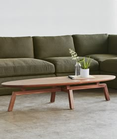 a living room with a couch, coffee table and vase on the floor in front of it