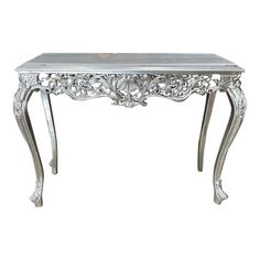 an ornate silver console table with glass top