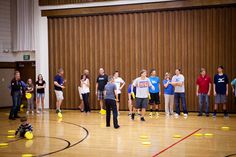 a group of people standing on top of a gym floor with frisbees