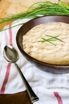 a wooden bowl filled with food on top of a white and red towel next to a spoon