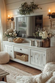 a living room with white furniture and flowers on the tv stand in front of it