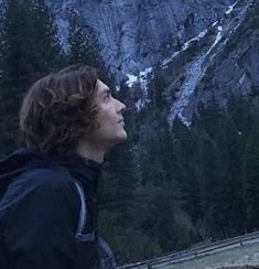 a young man standing in front of a mountain