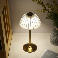 a table lamp sitting on top of a white counter next to a vase filled with flowers