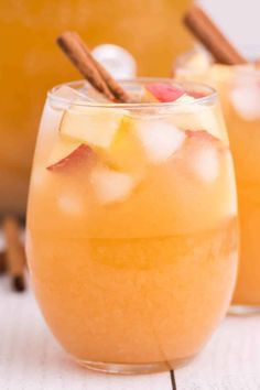 two glasses filled with apple cider on top of a table