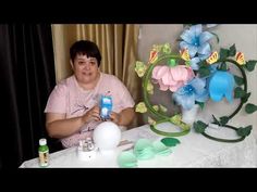 a woman is sitting at a table with flowers and water bottles in front of her