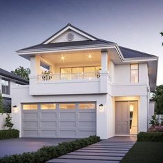 a white two story house with an attached porch and garage on the second floor is lit up at night