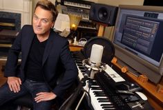 a man is sitting in front of a keyboard and sound mixing equipment at a recording studio