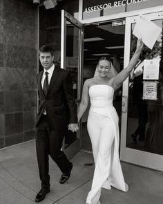 black and white photograph of a bride and groom exiting the building with their hands in the air