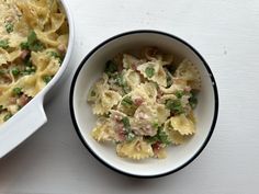 a bowl filled with pasta and peas next to a casserole dish on a table