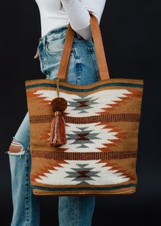 All our western lovers - this duffel is for you! Our restocked brown, rust, teal and cream Aztec inspired tote is a must have for all of your travels - big & small - this year!  Brown, rust and teal Aztec inspired tote Multicolored pom tassel detail Leather suede straps Measures 16" x 6" x 17" Designed in the U.S.A. Produced in India.  100% Cotton Lining: 100% Polyester Aztec Bag, Western Tote Bags, Gold Balayage, Fall Tote Bag, Fall Tote, Flannel Sweatshirt, Blouses Vintage, Bag Inspiration, Knitted Hats Kids