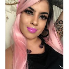 a woman with long pink hair and piercings on her nose is posing for the camera