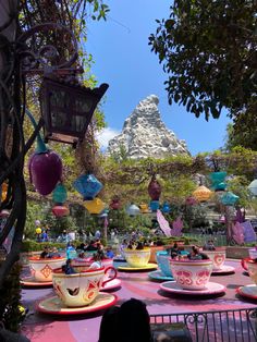 tea cups and saucers are sitting on a table with an umbrella in the background