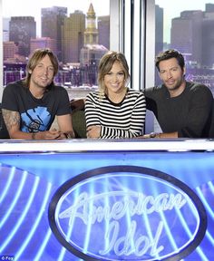 three people are sitting at a table in front of a window with the words american idol on it