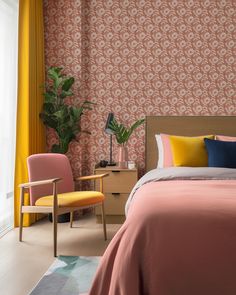 a bedroom with a bed, chair and wallpaper in pink and yellow colors on the walls