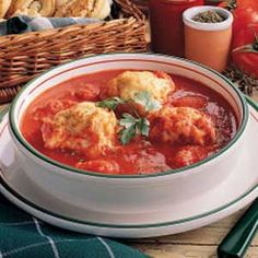 a white bowl filled with soup next to bread and tomatoes