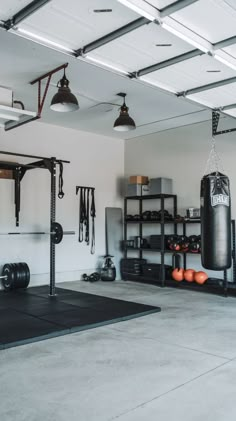 an empty garage with gym equipment and punching bags on the floor in front of it