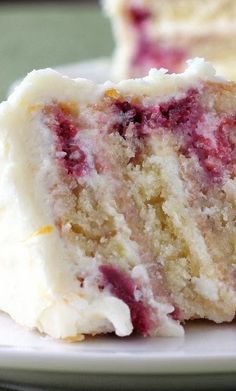 a slice of cake with white frosting and raspberry filling on a plate