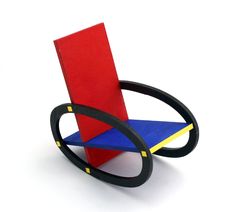 a red and blue chair sitting on top of a white table next to a pair of black scissors