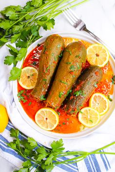 two fish fillets on a plate with lemons and parsley next to it