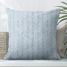 a blue and white pillow sitting on top of a bench next to a potted plant