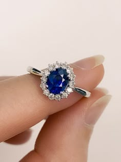 a woman's hand holding a blue and white ring with diamonds on the band