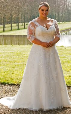 a woman standing in front of a lake wearing a wedding dress