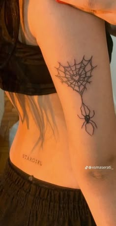 a woman with a spider web tattoo on her left arm and the word startii written in black ink