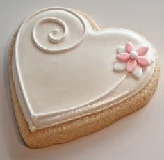 a decorated cookie in the shape of a heart with arabic writing and a flower on it