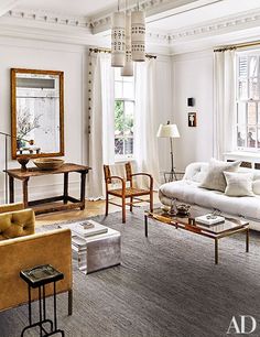 a living room filled with white furniture and lots of window sill space next to a large mirror