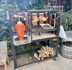 an outdoor grill made out of firewood and other items on a table outside in front of some bushes