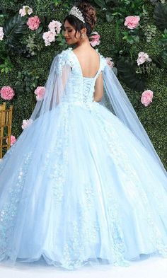 a woman in a blue wedding dress standing next to a flower wall with pink flowers