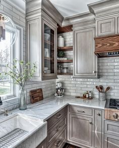 a kitchen with gray cabinets and marble counter tops