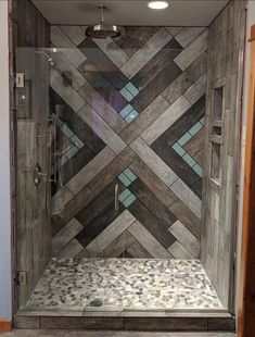 a walk in shower with wooden floors and tiled walls, along with a glass door