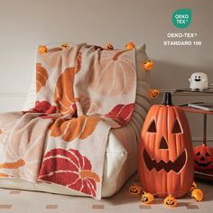 two pumpkins sitting on the floor next to a chair with a blanket over it