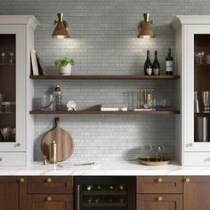 a kitchen with wooden cabinets and marble counter tops, wine bottles on the shelves above