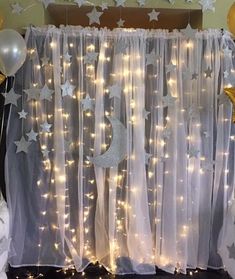 a curtain with stars and moon lights hanging from it's side next to balloons