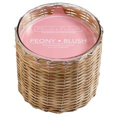 a wicker basket with a pink candle in the center and label on it that says peony & blush