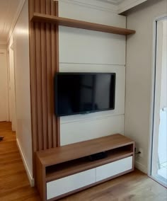 a flat screen tv sitting on top of a wooden entertainment center next to a sliding glass door