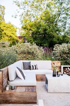 a white couch sitting on top of a wooden table next to a fire place in a garden