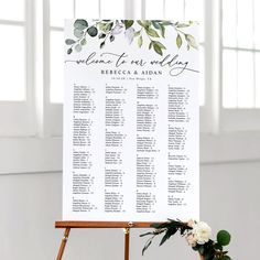 a wooden easer with a seating chart on it and flowers in the foreground