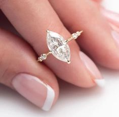 a woman's hand holding a ring with two pear shaped diamonds on top of it