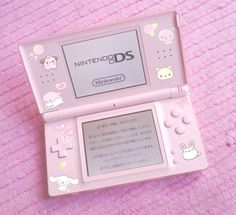 a pink nintendo ds sitting on top of a pink blanket