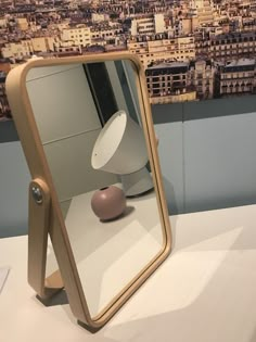 a table with a mirror and a lamp on it in front of a cityscape