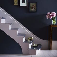 there is a vase with flowers and shoes on the floor next to some stairs that are painted blue