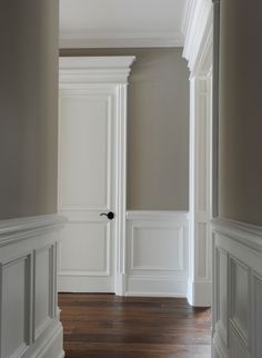 an empty hallway with wood floors and white walls