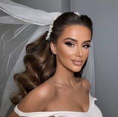 a woman wearing a bridal veil with her hair in a ponytail and makeup on her face